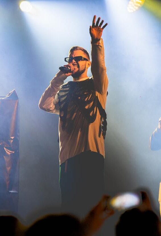 Artist performing live on stage with the crowd filming